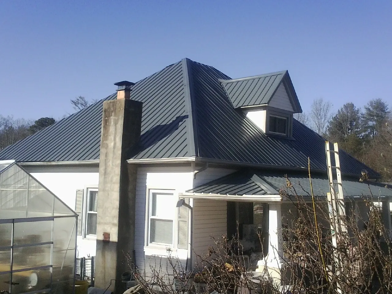 Dark blue standing seam metal roof on a white farmhouse with dormer — Slate & Tile Roof Repair by Roofing Brothers in Cape May Court House