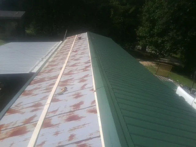 Old rusted panels beside newly installed green metal roofing — Wind Damage Roof Repair by Roofing Brothers in Cape May Court House