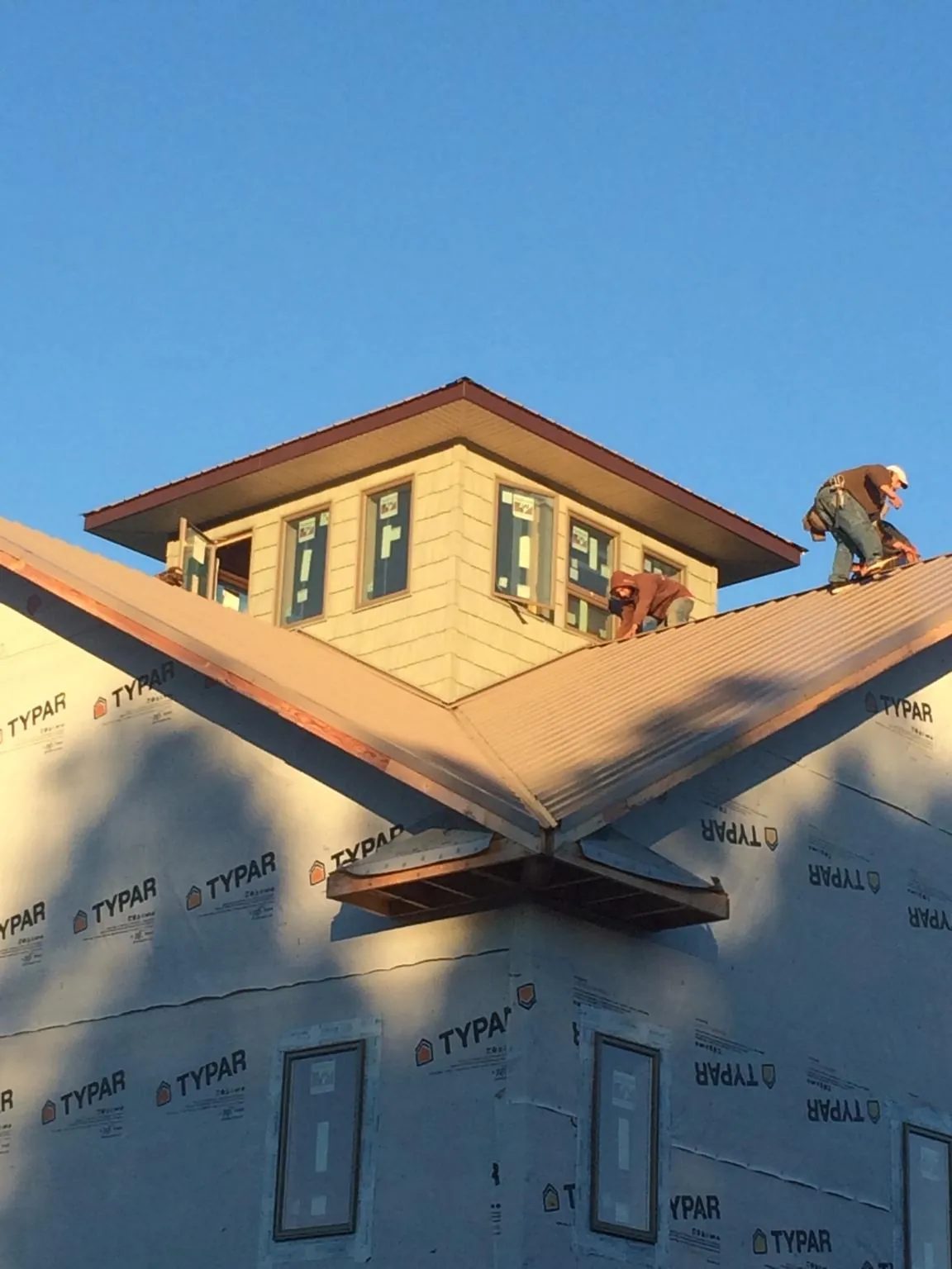 Roofers working around a rooftop cupola on a new metal roof at sunset — Roof Waterproofing in Cape May Court House by Roofing Brothers
